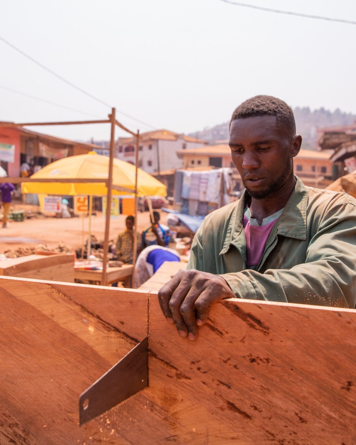 A carpenter cuts a board with a hand saw in his workshop in Africa